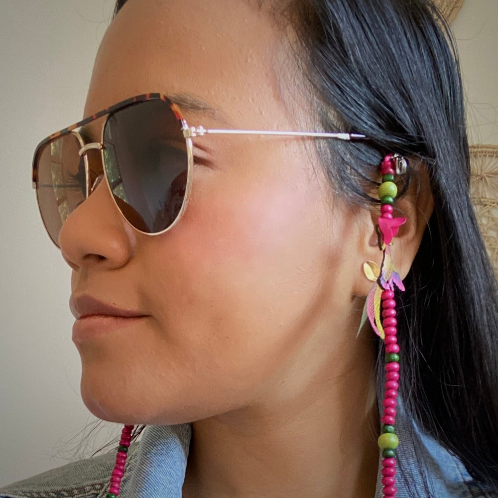 Model wearing sunglasses chain with pink anna hummingbird detail. 