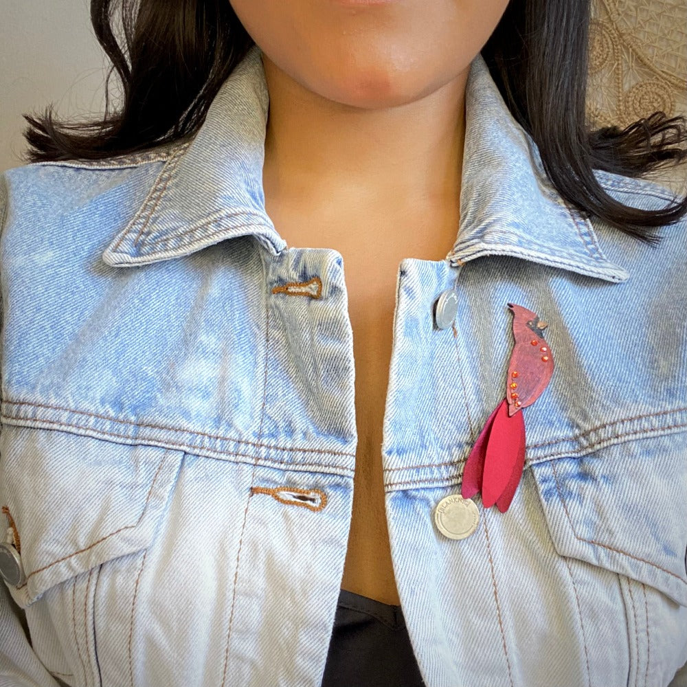 Model wearing a Cardinal Brooch on a jean jacket.  Handmade in Colombia.