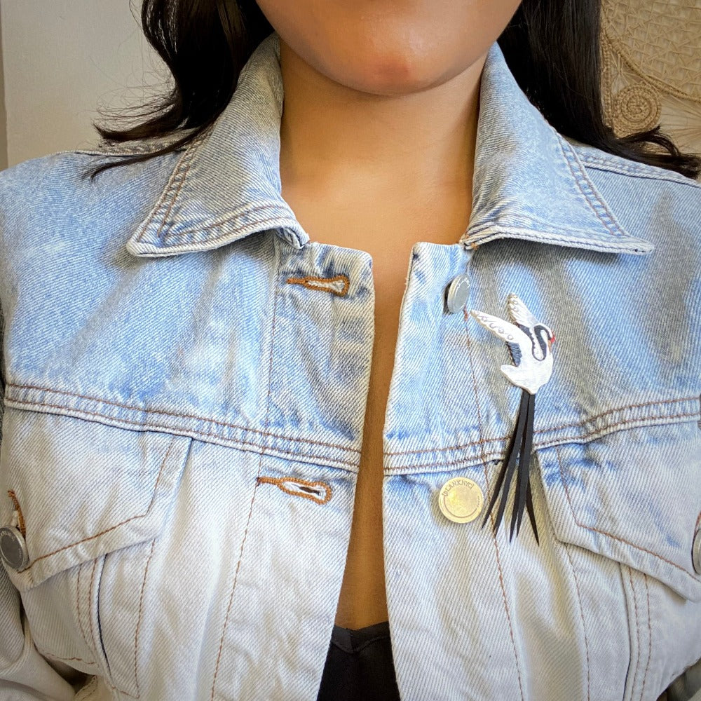 Model wearing Crane brooch on jean jacket.  Handmade in Colombia.