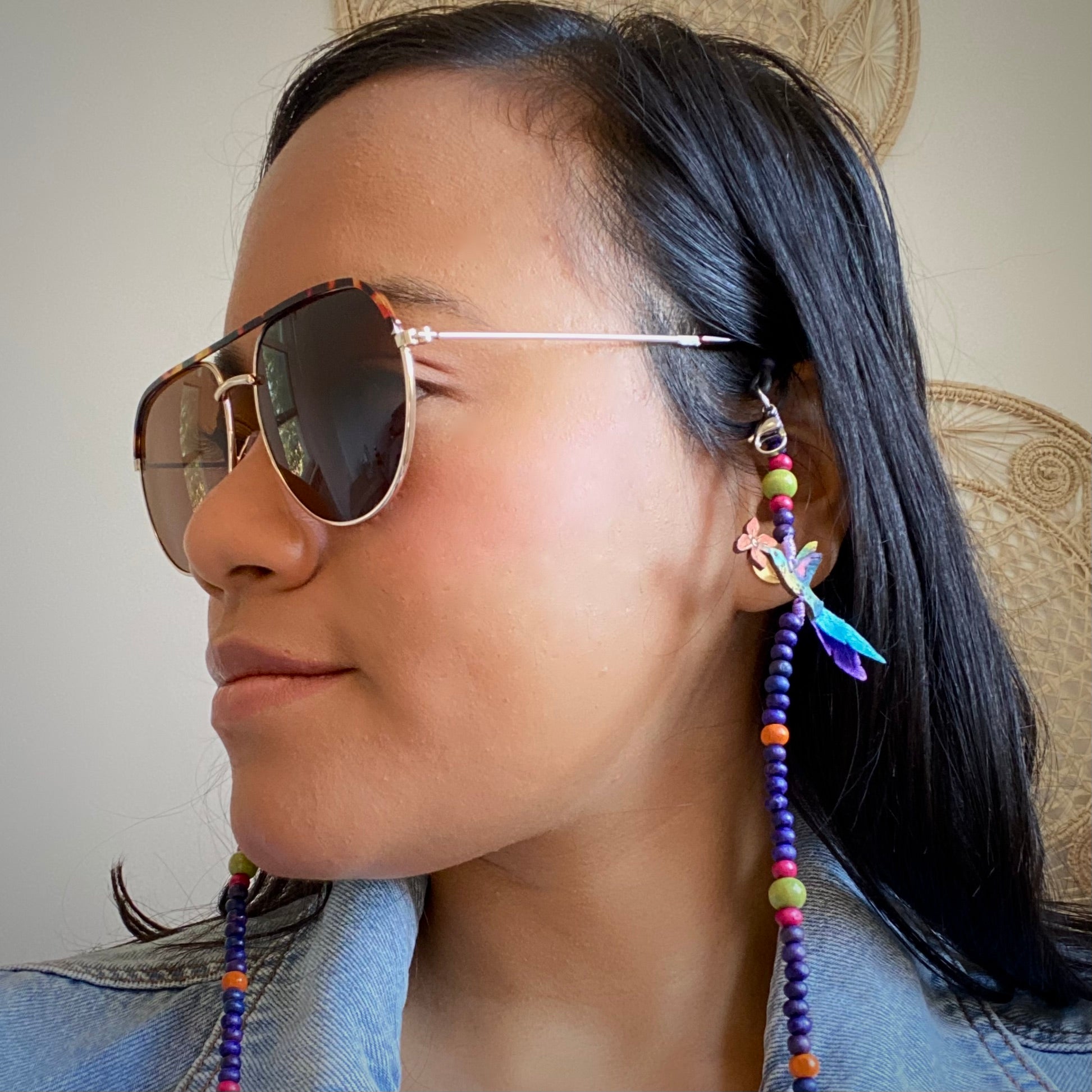 Model wearing eyeglasses chain with ruby throated hummingbird.  Handmade in Colombia. 