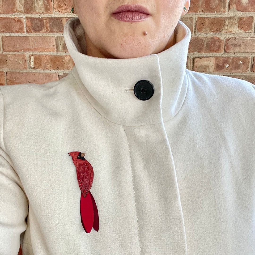 Cardinal Brooch on model wearing white wool coat.