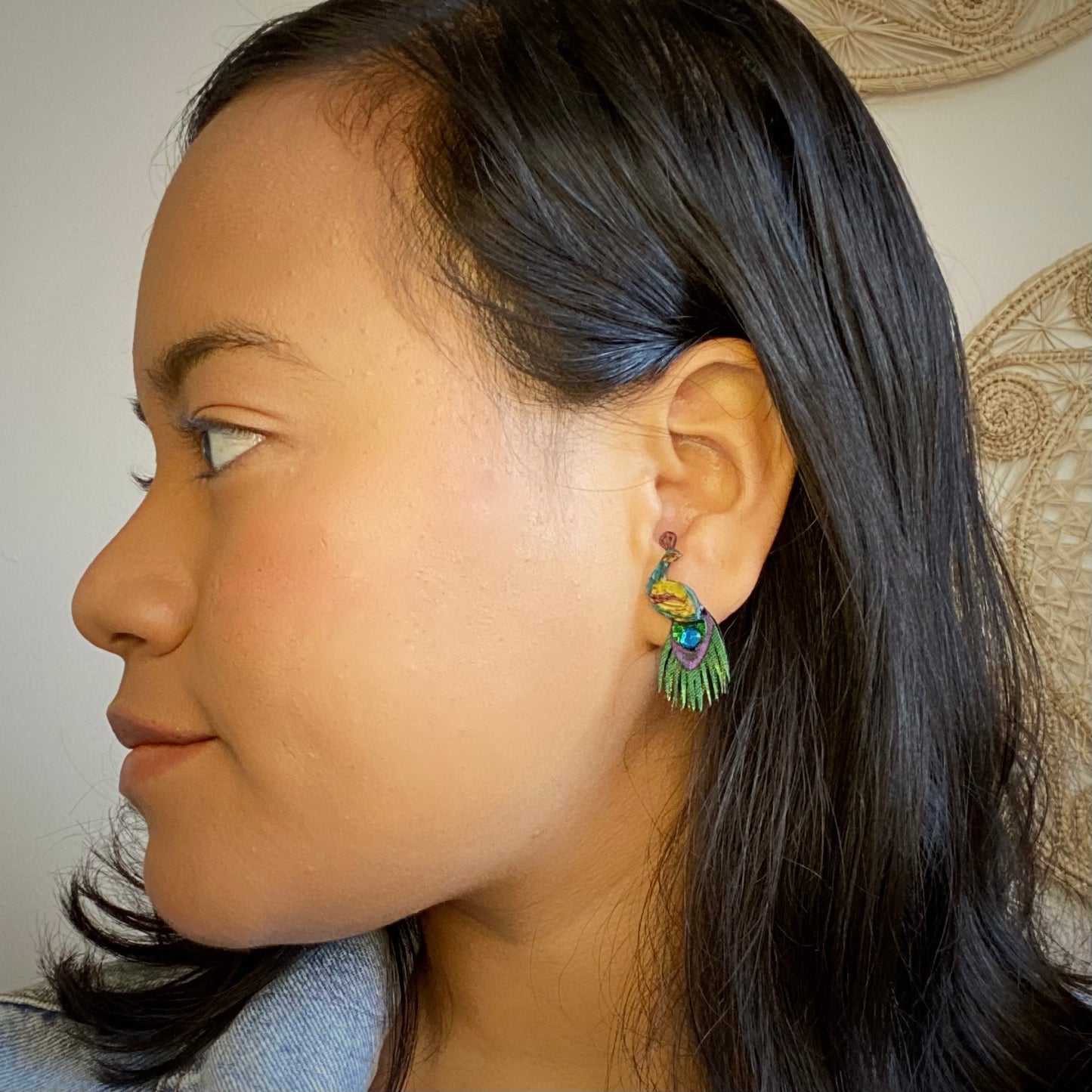 Small peacock earring studs on model. Handmade in Colombia.